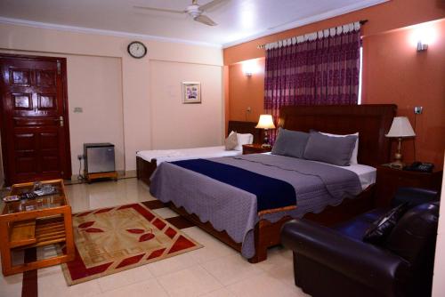 um quarto com uma cama grande e um sofá em Mir Continental Hotel & Restaurant em Muzaffarabad
