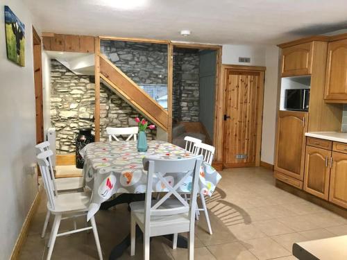 a kitchen with a table with chairs and a stone wall at Hayfellside Cottage, Sleep 6,3 Bedrooms(1 ensuite) in Kendal