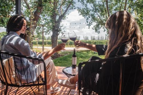 two people sitting at a table with a glass of wine at Lodwine Lodge Apartments in Ciudad Lujan de Cuyo