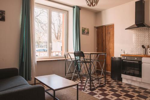 een woonkamer met een tafel en een keuken bij Joli logement centre ville avec clim in Orange