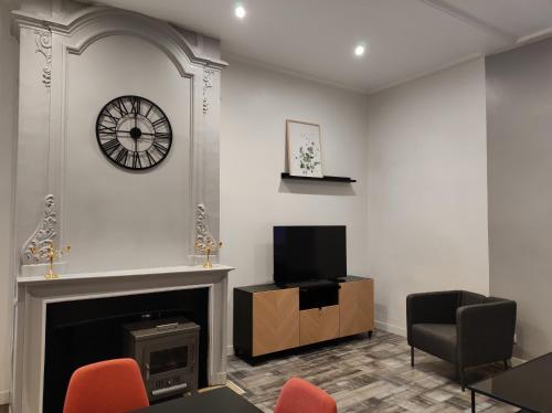 a living room with a fireplace and a clock on the wall at La Marlienne - Appartement T3 dans un château 