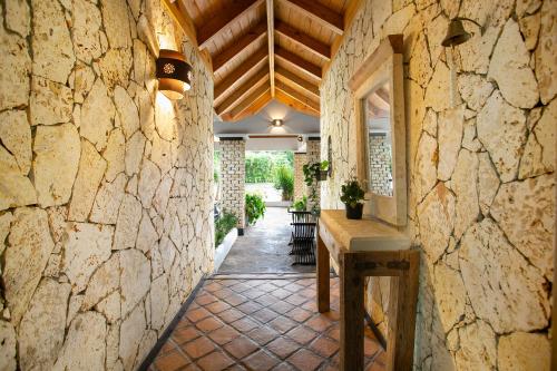 pasillo de piedra con mesa y pared de piedra en Fontana di Rosa, African Style Villa Casa de Campo en La Romana