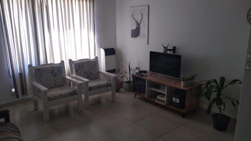 a living room with two chairs and a flat screen tv at Los Palos Ribera Norte in Playa Unión