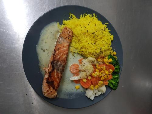 a plate of food with rice and meat and vegetables at Tattoo PENSION mit Restaurant und Tattoo-Studio in Mörtschach