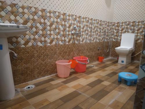 a bathroom with a toilet and buckets on the floor at Happy Homestay in Khajurāho