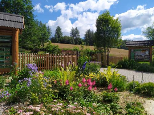 a garden with flowers in front of a fence at Srub Javorná - apartmány Šumava in Javorná