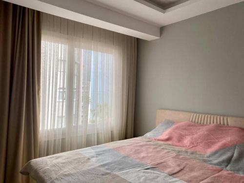 - une chambre avec un lit à côté d'une fenêtre dans l'établissement Sahil One bedroom Apartment, à Mezitli