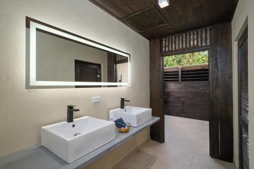 Hawksbill Resort Antigua - All Inclusive في Five Islands Village: حمام به مغسلتين ومرآة كبيرة