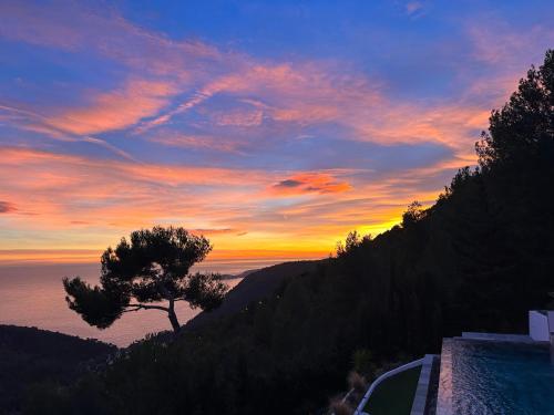 a sunset with a tree on the side of a hill at A Eze , Bas de villa piscine près de Monaco in Èze