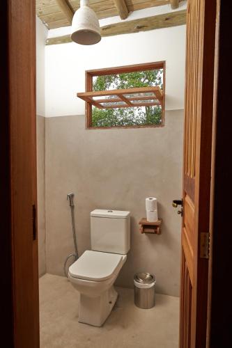 a bathroom with a toilet and a window at Suíte Baleia in Caraíva