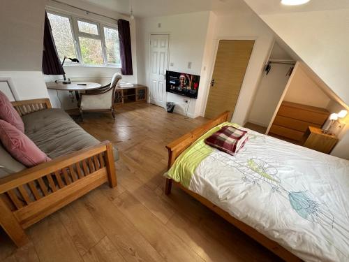 a bedroom with a bed and a table in a room at Ashcroft Quiet Garden House-London Luton Airport in Luton