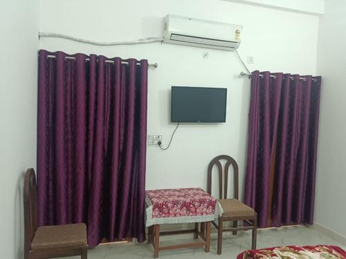 um quarto com cortinas roxas e uma mesa e cadeiras em Maa vaishno paying guest house em Ayodhya