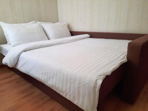 uma cama grande com lençóis brancos e almofadas em Двокімнатна квартира в центрі біля готелю Палаццо Мережа Alex Apartments Безконтакнте заселення 24-7 em Poltava