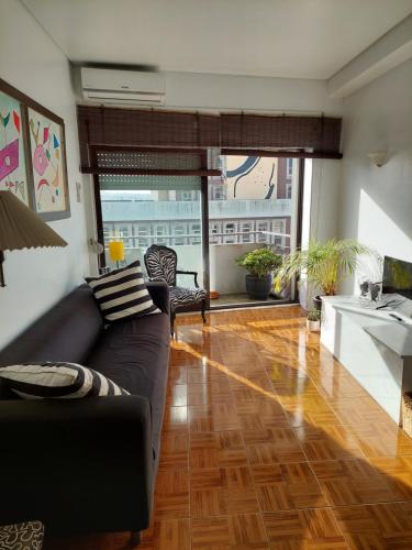 a living room with a black couch and wooden floors at Trindade Apartment in Porto