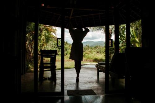 a person walking into a house with an umbrella at Sunrise Paradise Bali in Karangasem