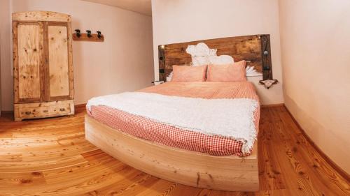 1 dormitorio con 1 cama grande y suelo de madera en B&B Maso Ghirola en Pinzolo