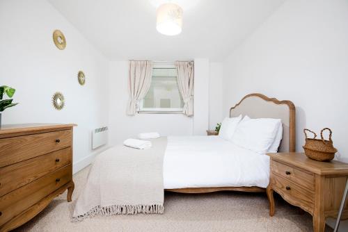 1 dormitorio con cama blanca y tocador de madera en 2 Bed 2 Bath Close to Big Ben en Londres