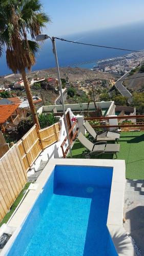 a swimming pool with chairs and a view of the ocean at Nueva Casa rural piscina privada in Santa Cruz de Tenerife