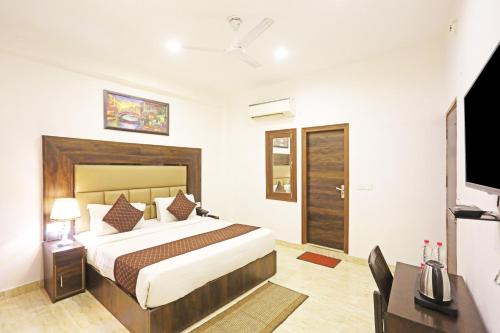 a bedroom with a bed and a desk and a television at Hotel De Kiara Near Delhi Airport in New Delhi