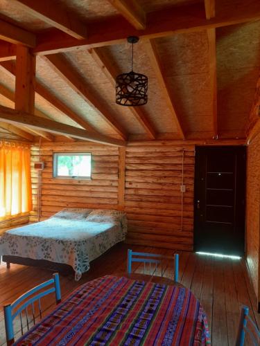sypialnia z łóżkiem w drewnianym domku w obiekcie Cabaña Camila w mieście El Bolsón