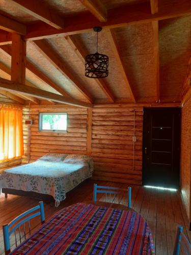 Un dormitorio con una cama en una cabaña de madera. en Cabaña Camila, en El Bolsón