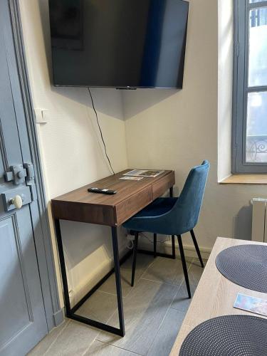 Elle comprend un bureau avec une chaise bleue et une télévision murale. dans l'établissement Le bleu velours, studio centre ville historique, à Bourges
