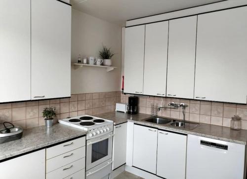 una cocina blanca con armarios blancos y fregadero en Valoisa & tilava 3.krs kaksio, lasitettu parveke, en Kouvola