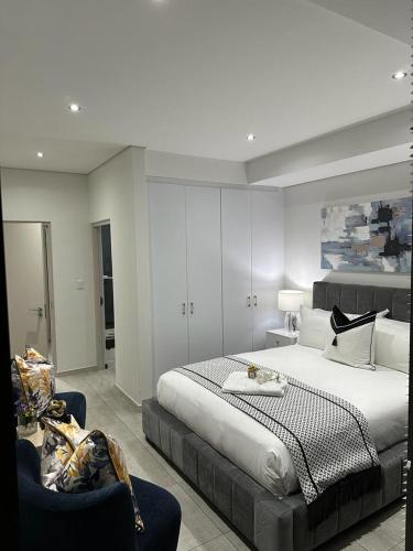 a bedroom with a large bed and two chairs at Delight Luxurious Apartments in Johannesburg