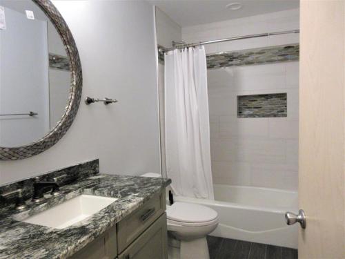 a bathroom with a sink and a toilet and a mirror at Close Walk To The Beach, The Perfect Home For A Single Family, in Harvey Cedars