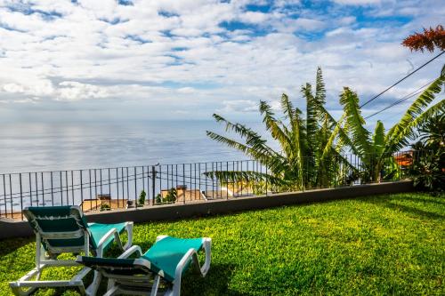 two chairs sitting on the grass near the ocean at Apartamento Domingos in Arco da Calheta