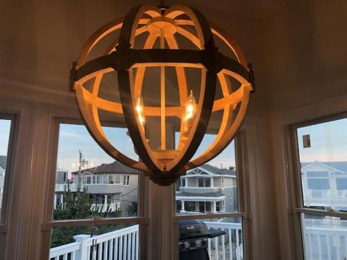 a chandelier hanging in a room with a window at 4Th From The Ocean! Sleeps 10! in Harvey Cedars