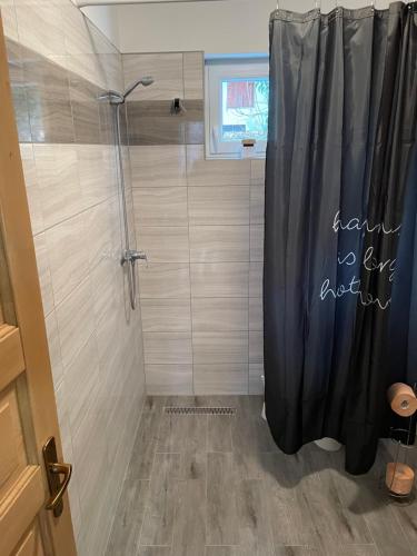 eine Dusche mit einem schwarzen Duschvorhang im Bad in der Unterkunft Ponty Apartman in Kunfehértó