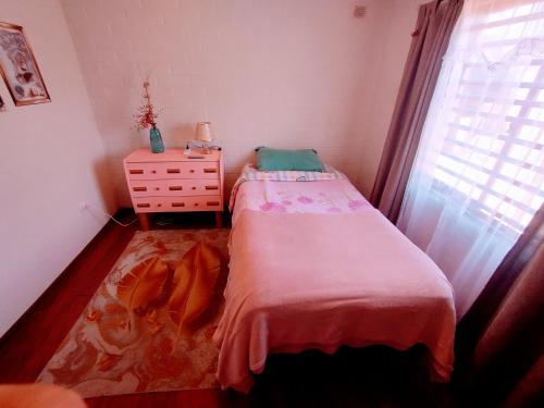 ein Schlafzimmer mit einem Bett, einer Kommode und einem Fenster in der Unterkunft Habitación hogareña in Curicó