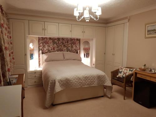 a bedroom with a bed and a desk and a chandelier at Barn Court Bed and Breakfast in Everton