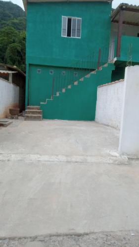 a building with a green wall and stairs in front at Meu cantinho in Ubatuba