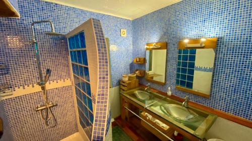 une salle de bain carrelée bleue avec un lavabo et une douche dans l'établissement La maison du Bougainvillier 10 personnes, à Dions