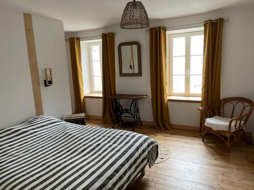 una camera da letto con un letto, una sedia e finestre di MAISON DE VILLAGE a Chambon-le-Château