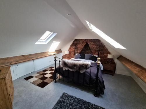 a attic bedroom with a bed in a brick wall at Hill View in Abertillery