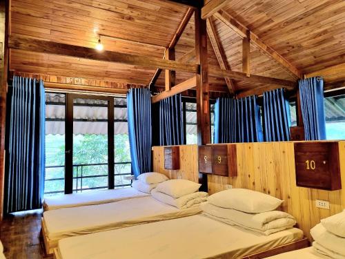2 camas en una habitación con paredes y ventanas de madera en Tavan Chopai Homestay, en Sa Pa