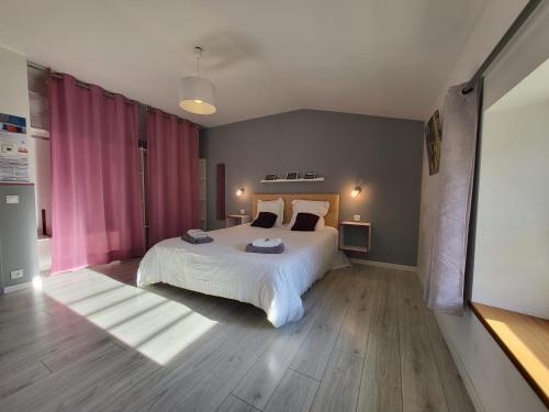 1 dormitorio con 1 cama blanca grande y cortinas rosas en Chambre d'hôte Le Clos d'Audio à Riols, en Riols