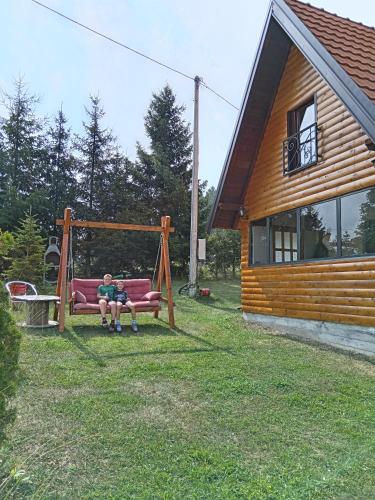 a person sitting on a swing in a yard next to a house at Kod Gruja in Ribnica