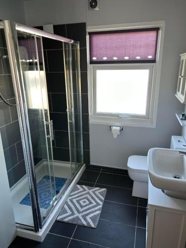 a bathroom with a shower and a toilet and a window at Modern One Bedroom Chalet with Central Heating in Bridlington