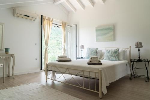 een witte slaapkamer met een bed en een raam bij Villa Eleonas in Strongylí