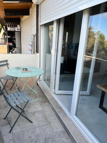 einen Tisch und einen Stuhl auf einer Terrasse mit Glasschiebetüren in der Unterkunft Coquette maison à 500 m de la plage du verdon à la couronne in Martigues