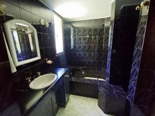 baño de azulejos negros con lavabo y ducha en hermosa casa a una cuadra del lago en San Carlos de Bariloche