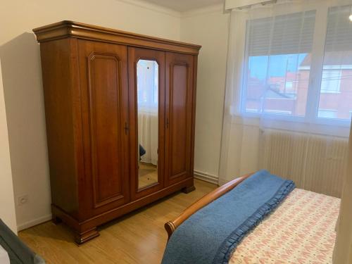 a bedroom with a wooden cabinet with a mirror at Maison 4 à 8 personnes in Faches-Thumesnil