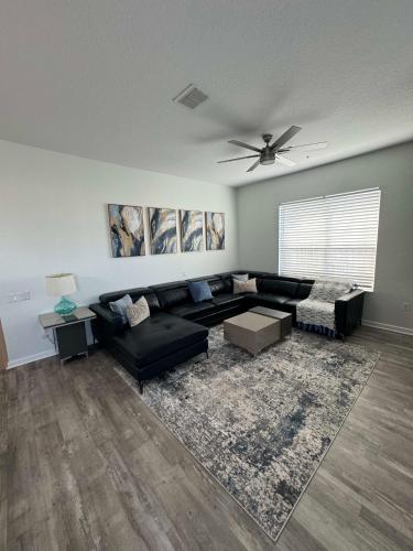 a living room with a black couch and a ceiling fan at The Epic Milan Penthouse Orlando in Orlando