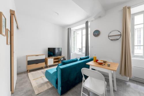 un salon avec un canapé bleu et une table dans l'établissement Les studios Jean Bringer - Carcassonne centre-ville, à Carcassonne
