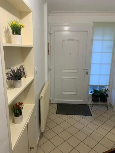 a hallway with a white door and shelves with plants at Maison 4 à 8 personnes in Faches-Thumesnil