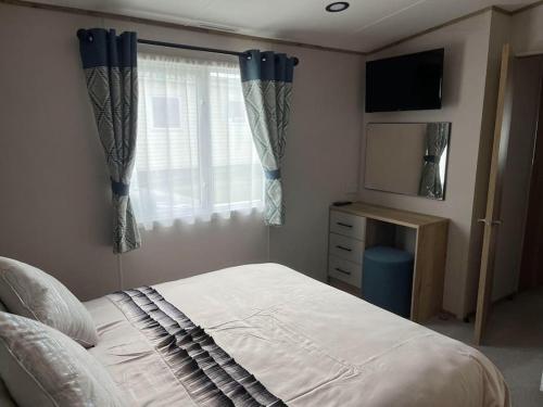 a bedroom with a bed and a window and a television at Coastal caravan with superb view in Bembridge